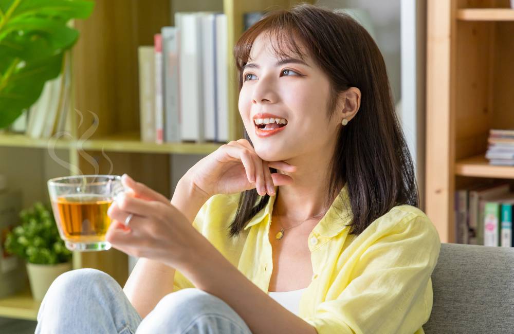 温かい飲み物を手に笑顔でくつろぐ女性